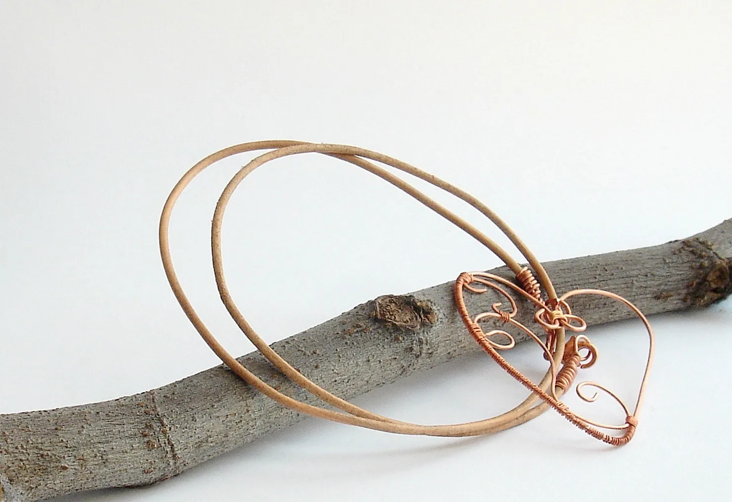 Copper wire wrapped heart pendant with natural leather string.