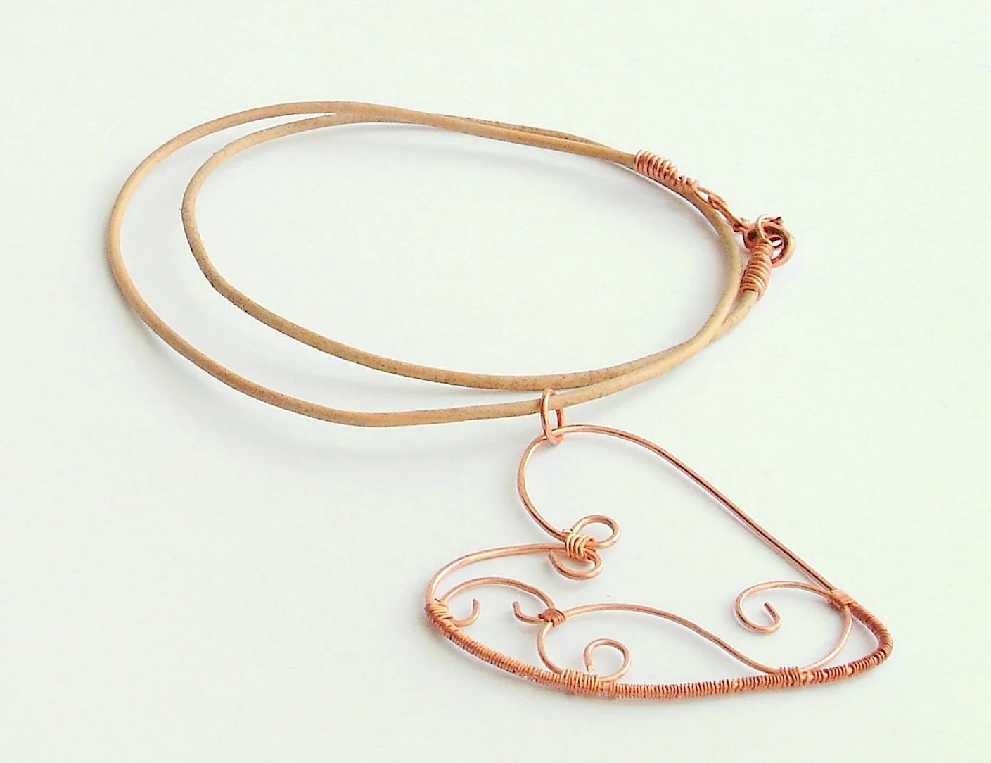 Copper wire wrapped heart pendant with natural leather string.